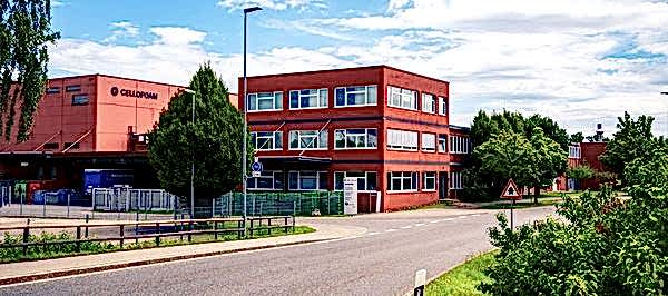 rotes Firmengebäude mit Produktionshalle umgeben von grüner Natur