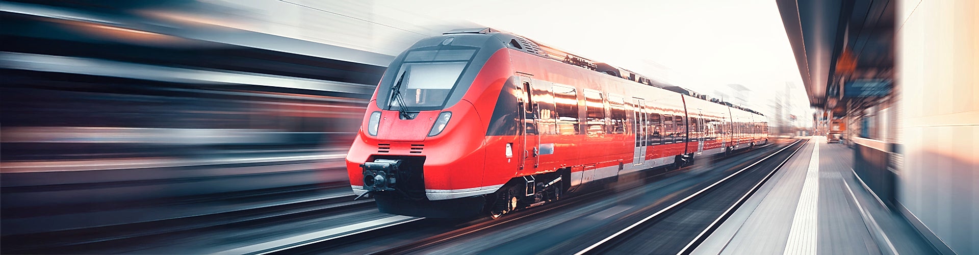 Ein roter Regionalzug fährt durch einen Bahnhof